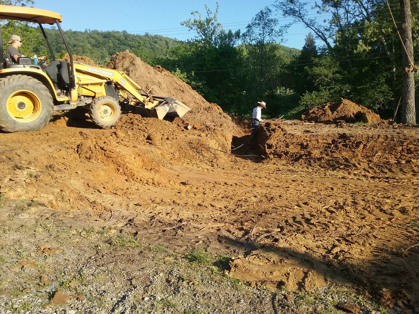 Backhoe excavating red clay on a cleared site