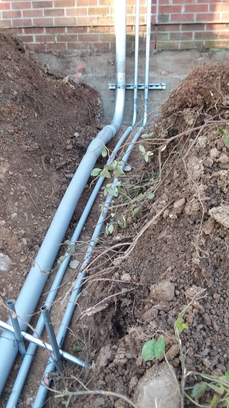 Conduit runs in an open trench beside a foundation