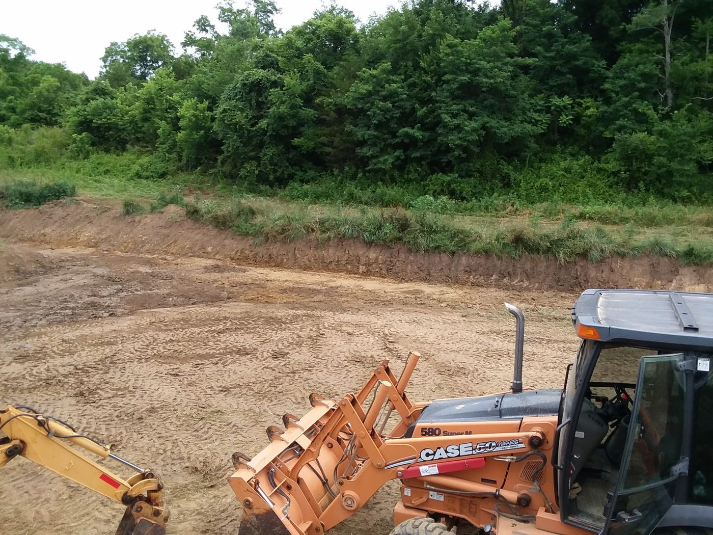 Graded building pad with a backhoe in the foreground