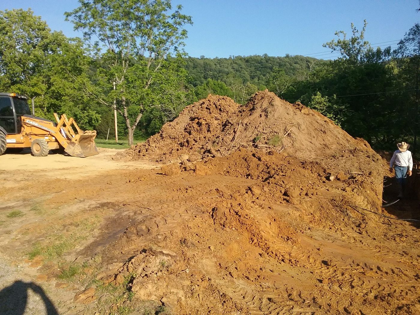 Excavated red clay stockpiled beside a backhoe